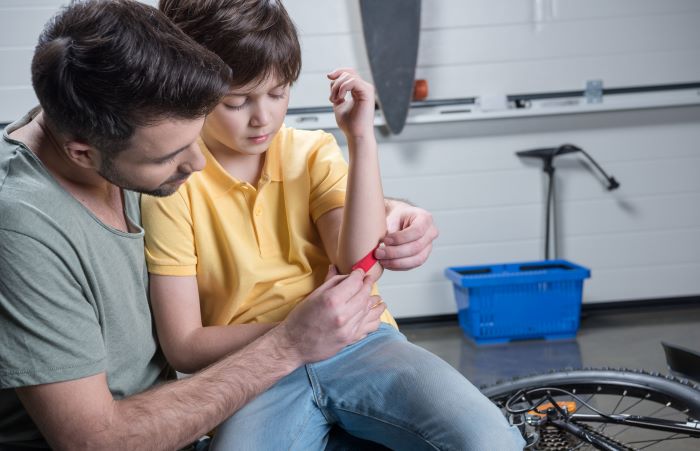 father treating son's elbow