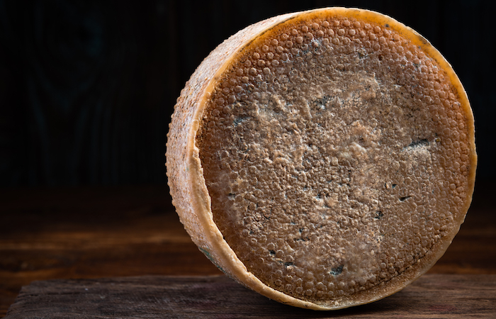 whole cheese wheel on a wooden board