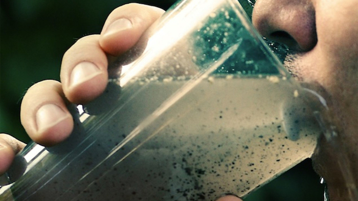 person drinking a glass of dirty water