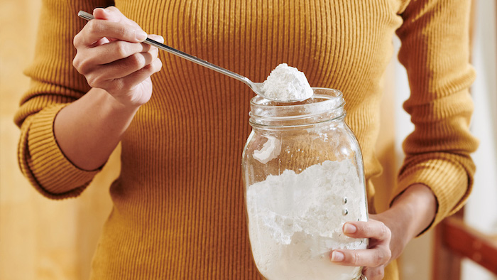 woman in yellow shirt spooning lye from a jar