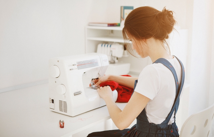 woman sewing a red garment on a sewing machine