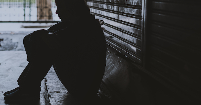 woman crouched in an alley