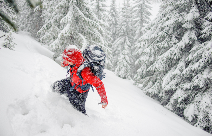 man climbing up a mountain in the snow