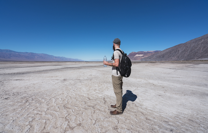 man in the desert with a water bottle, hiking