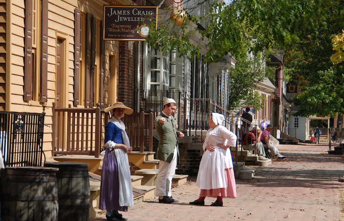 people in colonial clothing standing in a town