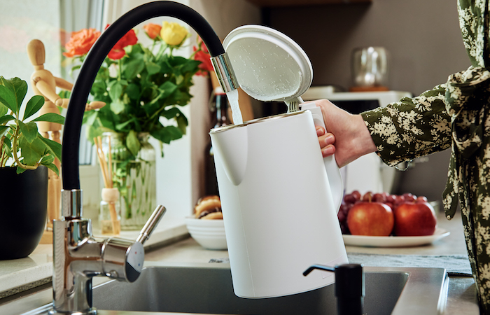 filling a tea kettle in a sink