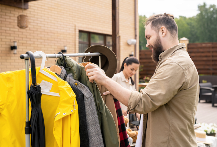 Man choosing clothes from a clothing rack at a yard sale. 