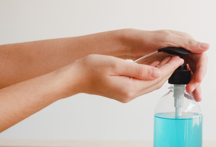 Woman squirting hand sanitizer into her hands made with rubbing alcohol.
