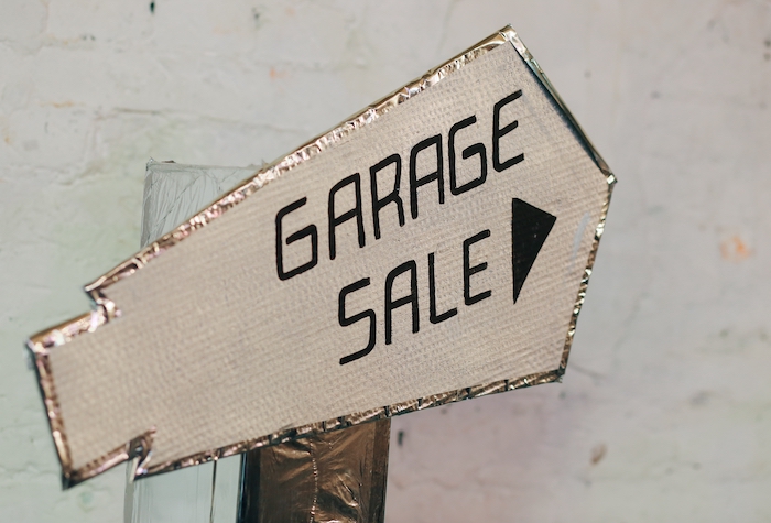 Homemade garage sale sign pointing in the direction of the sale.