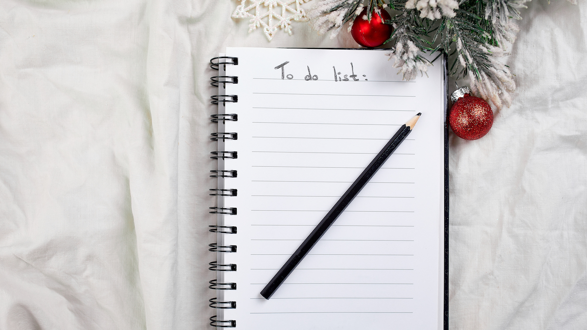 Top view of blank notebook with "To do list" written at the top and surrounded by green pine and red ornaments.