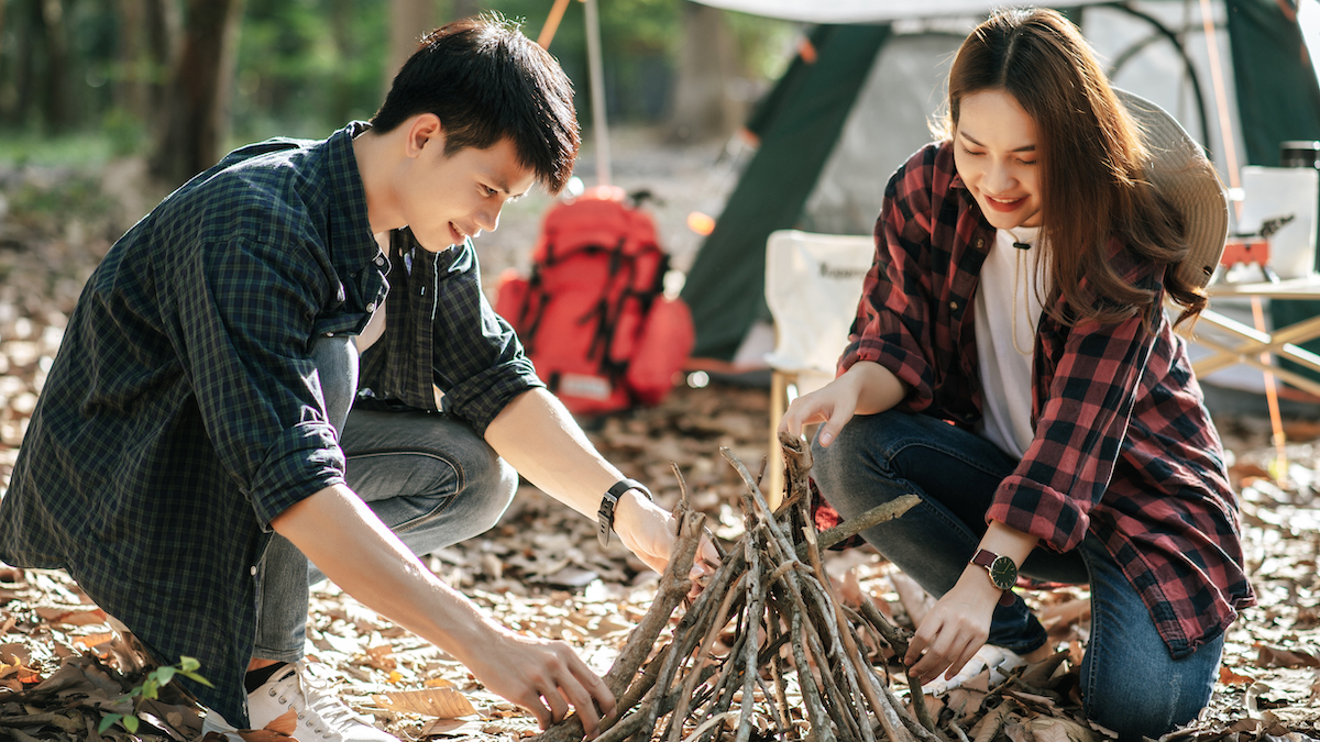 Young man and woman learning to prepare a traditional fire.