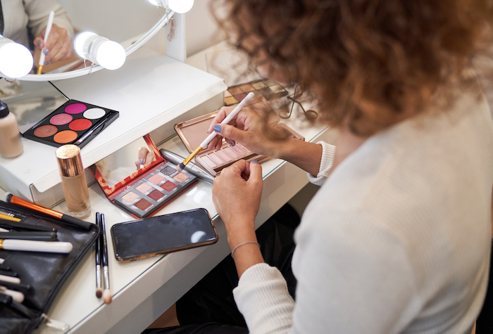 Woman using makeup at her vanity. 