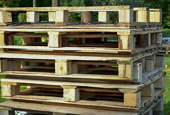A stack of used wooden pallets outdoors.