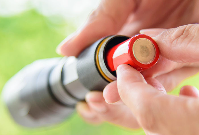 Person putting rechargeable batteries into a flashlight. 