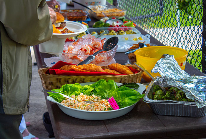 An outside table loaded with food options at a potluck.