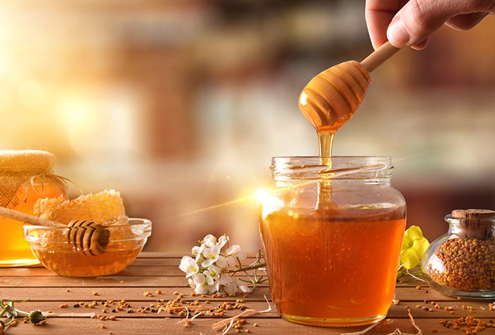 A person drizzling honey out of a honey jar.