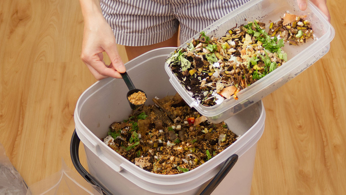A person adding to their compost bin.