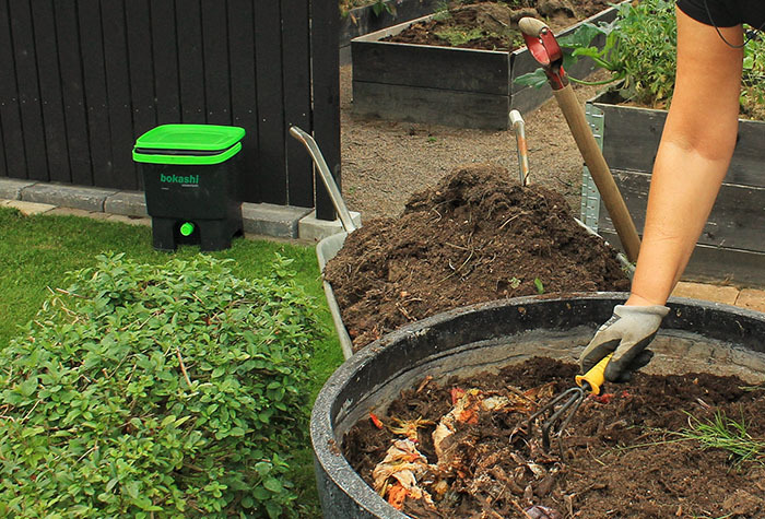 A person adding compost to their garden.