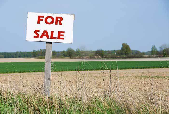 A "For Sale" sign on a large farm.