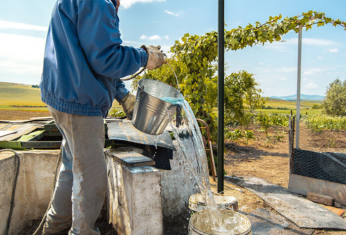 A man drawing water from a well on a farm.