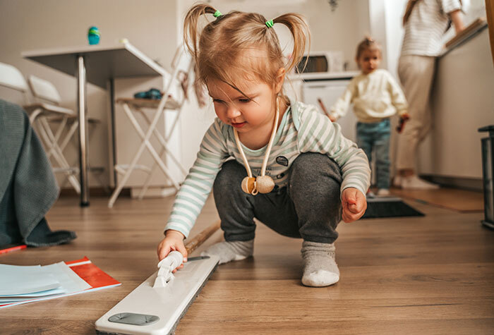 A little girl is helping sweep the floor.