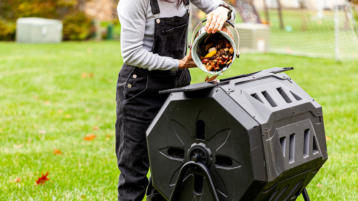 A person putting food scraps into their compost bin.