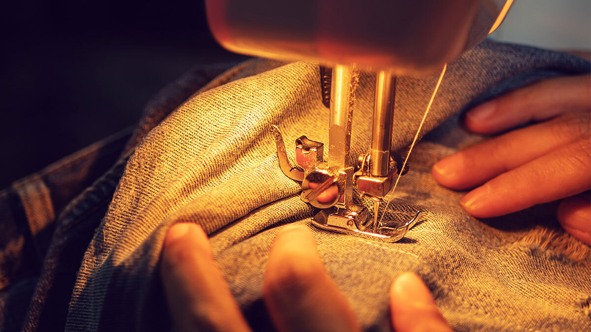 A person sewing at home on their sewing machine.
