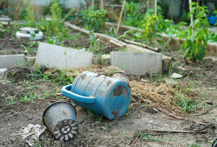 A watering can laying on its side in a dilapidated garden.